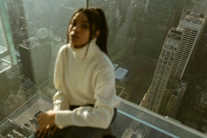 woman sitting on the glass platform of a tall building