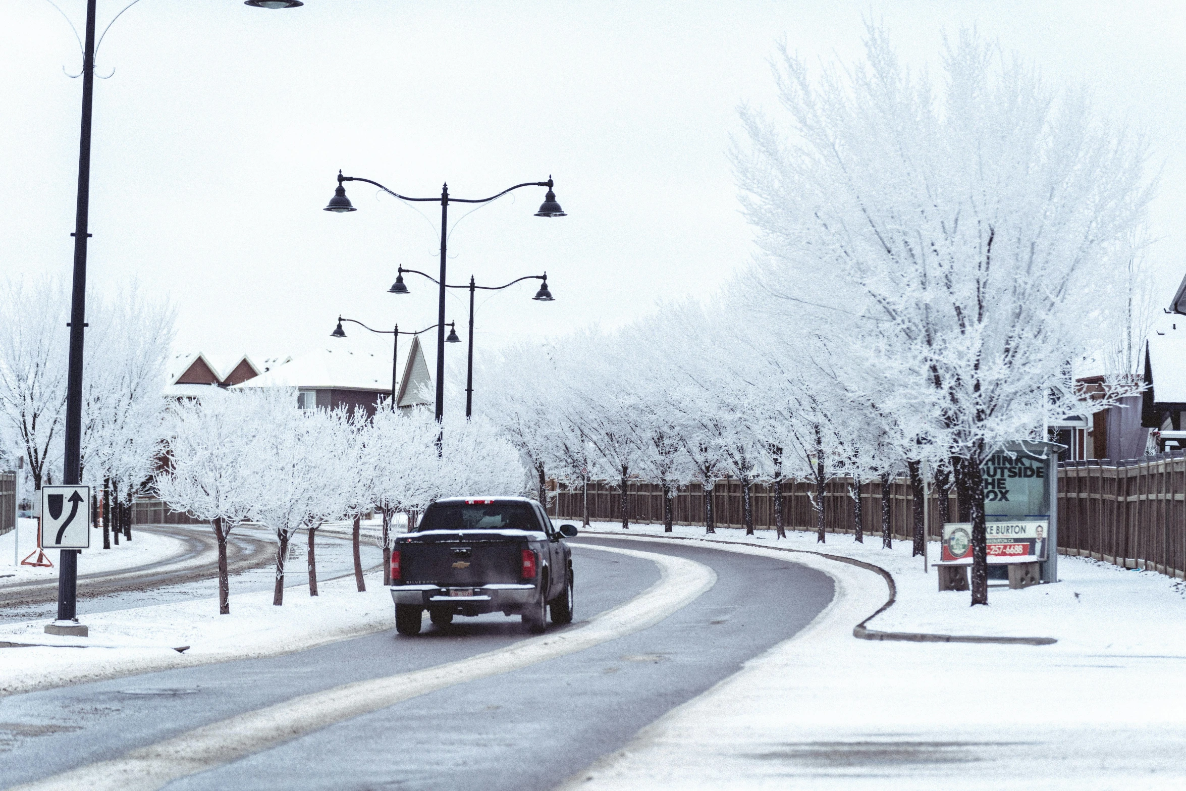 a car driving on a snowy road with power lines