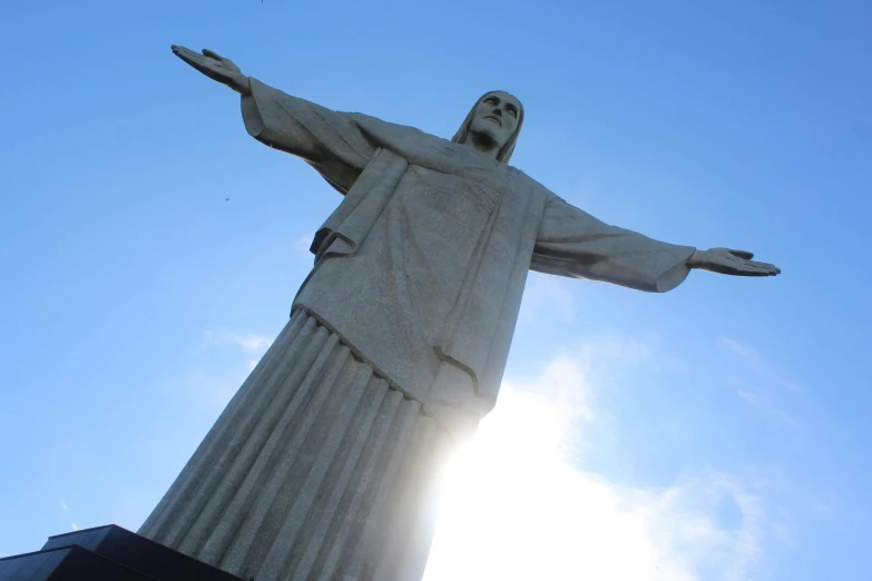 a statue of jesus is near the sun on a sunny day