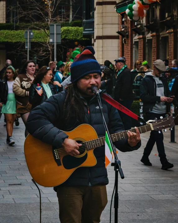 a street performer holding a guitar walking down the middle of a street