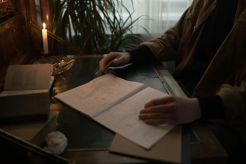 a woman sitting at a table writing on a paper