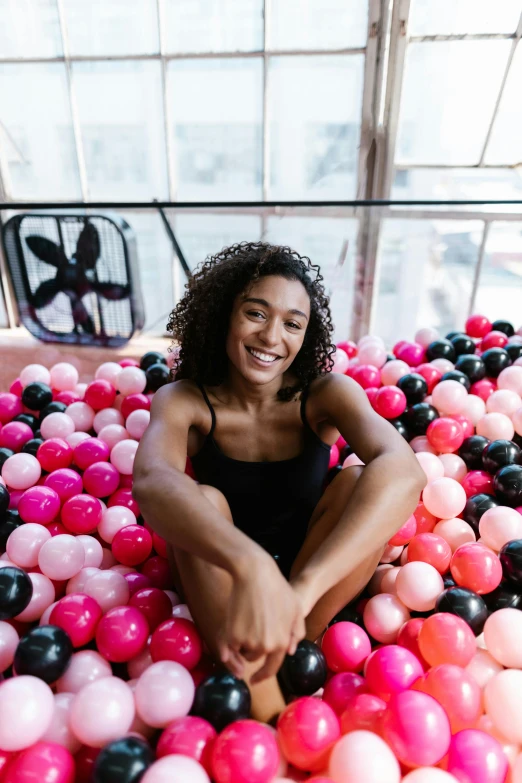 a young woman sitting in a bubble pool surrounded by balloons