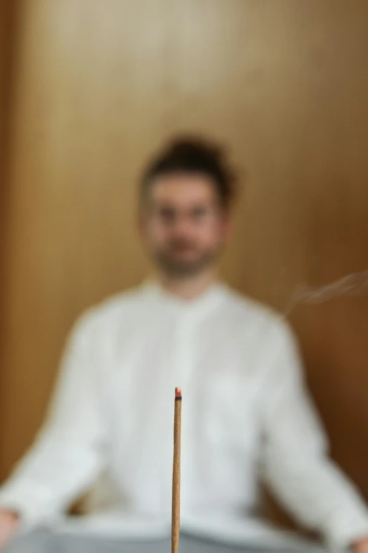 a guy with a white shirt standing behind a stick that has been turned red