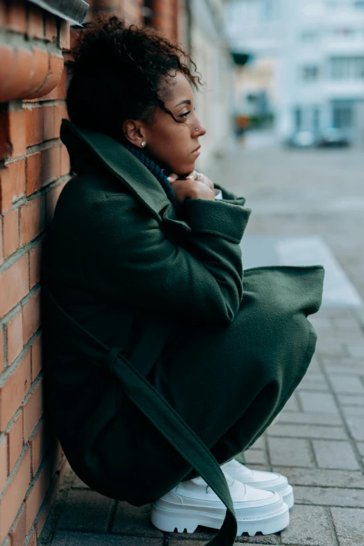 the young woman is posing by a brick wall