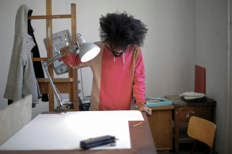 a woman in a pink shirt stands with a white light next to a table