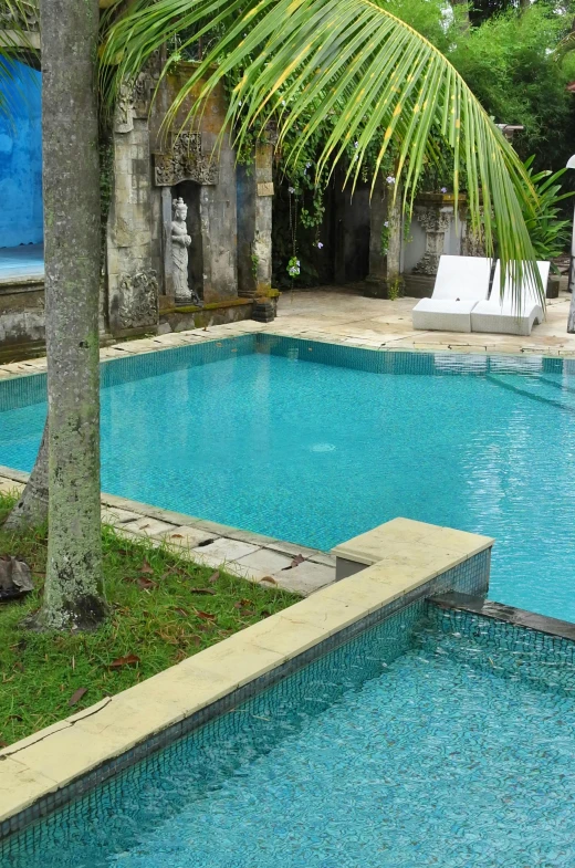 a blue pool with two lounge chairs on the side