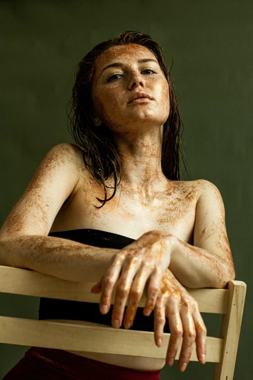 a woman without a shirt is sitting in a chair and has frecky hands reaching over the top of her shoulder