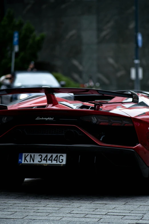 the back end of a red sports car parked on a brick road