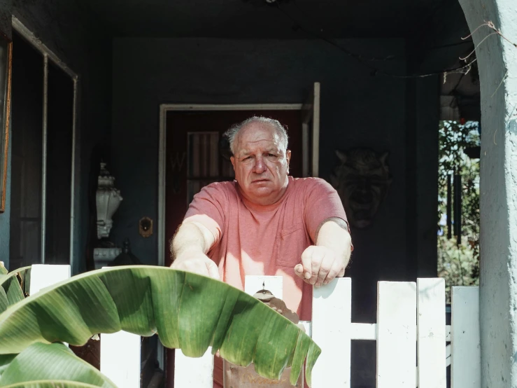 an old man leans over a fence to pose for a po