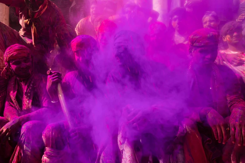 a group of people sit next to some purple smoke