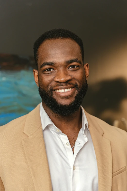 man in tan blazer smiling and posing for pograph