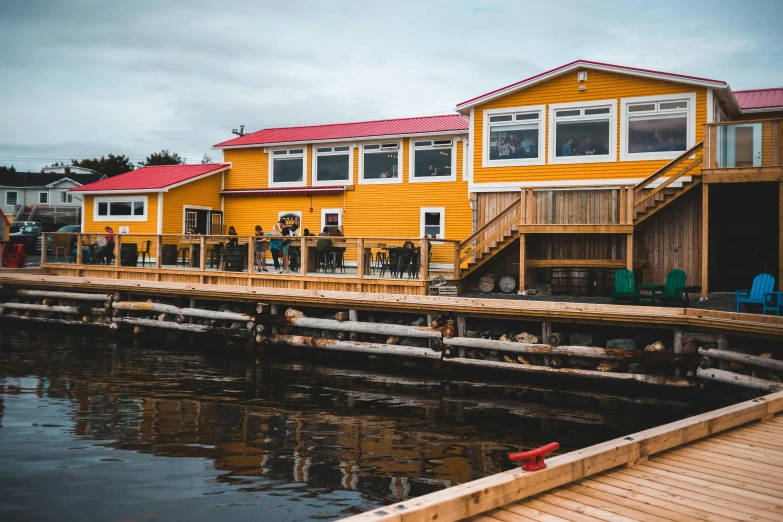 people stand on a dock next to some colorful houses