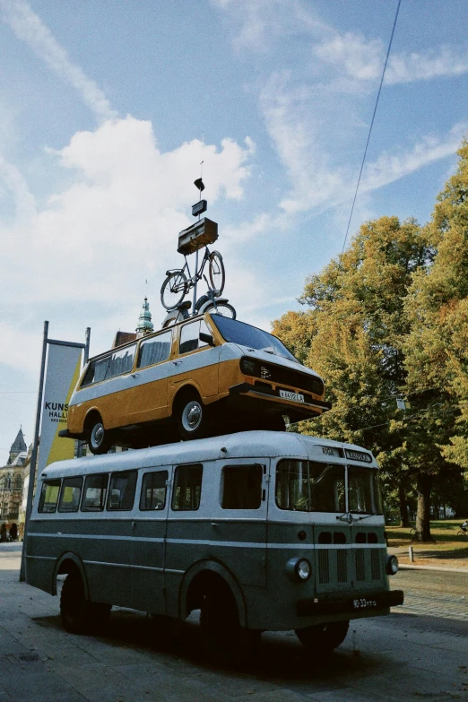 an old bus is with a car stacked on it