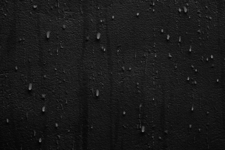 a black wall with several different drops of water