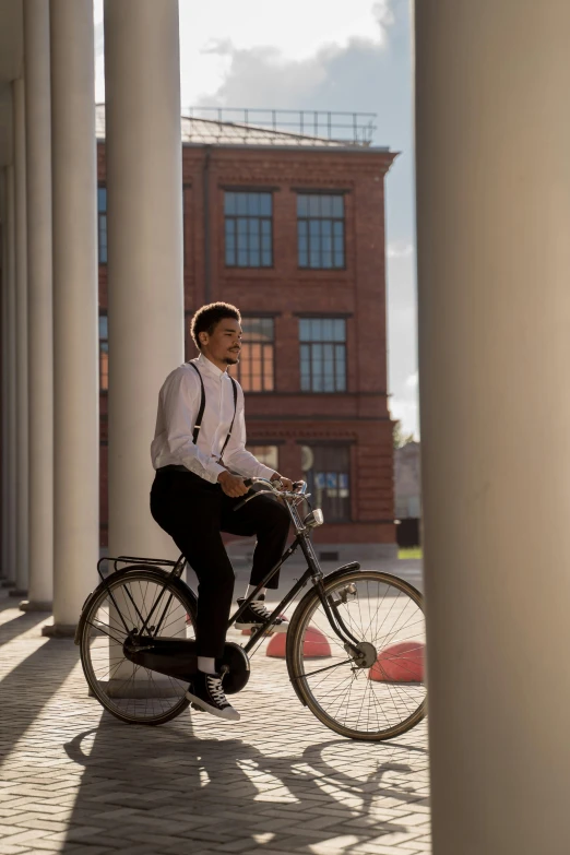 a man riding a bike underneath some big pillars