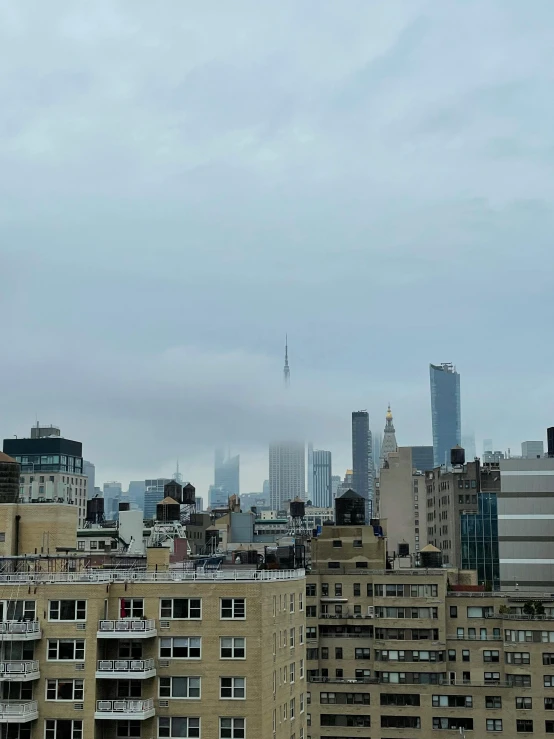 a bird flies in the cloudy sky near an urban area