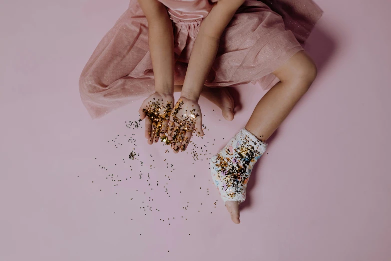 girl wearing sequins and a pink tutu holding up her hand with several crystals scattered about