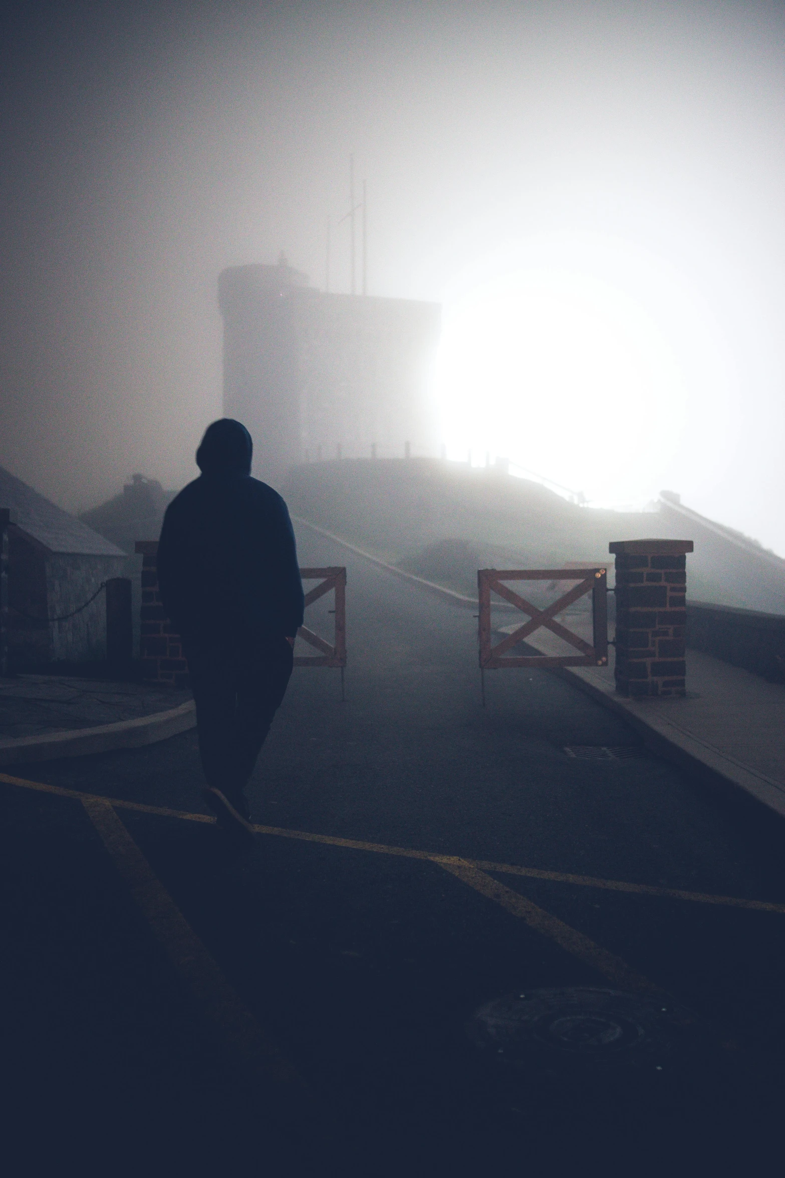 a silhouette of a man walking through a foggy scene