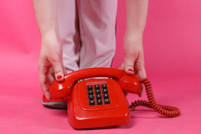 the woman with her foot on the phone is touching the red telephone