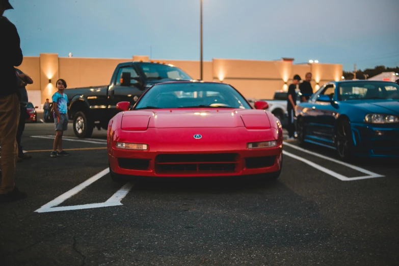 a red car sits in the parking lot near other vehicles