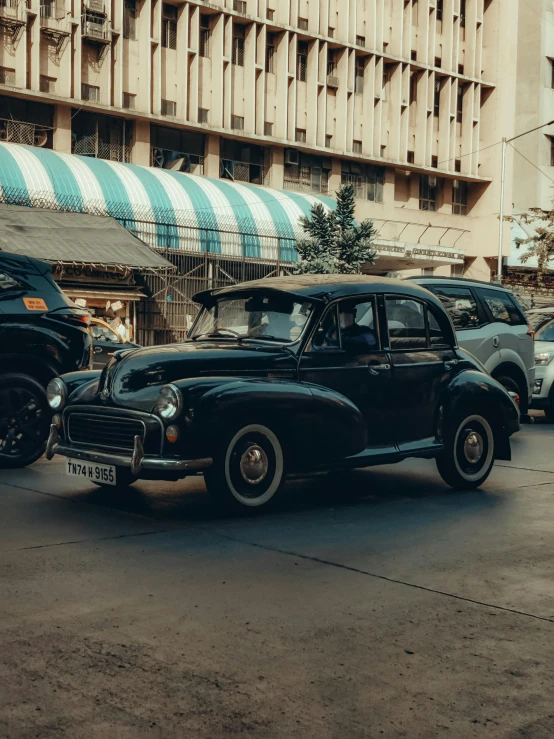 two vintage cars are parked along a side street