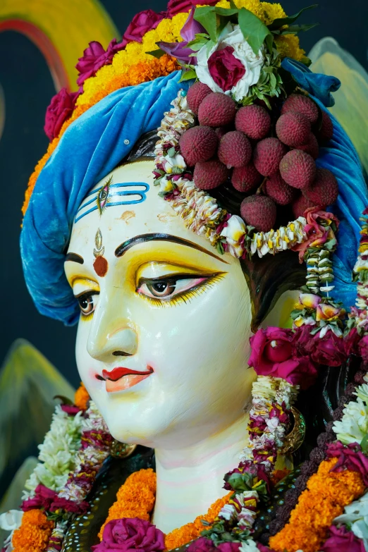 a statue of a hindu god with colorful flowers around his head