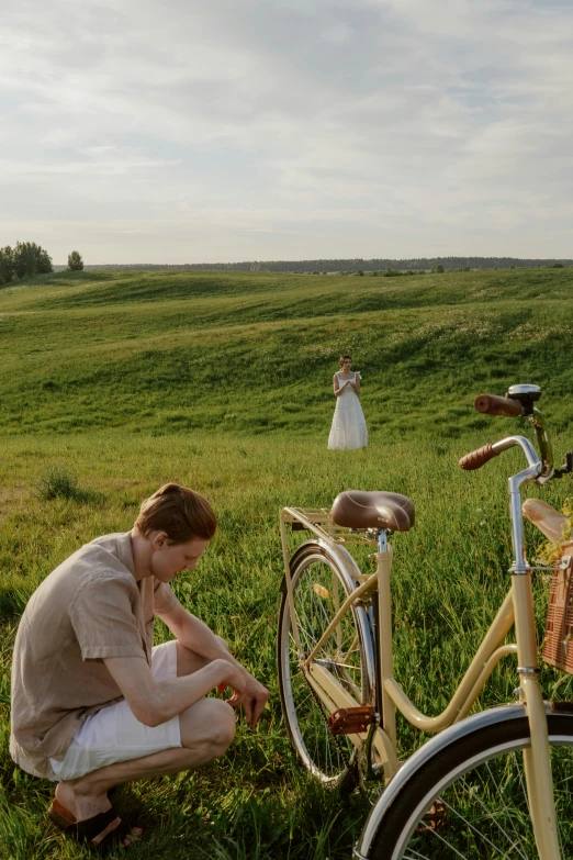 a woman sits with her bike and looks at the grass