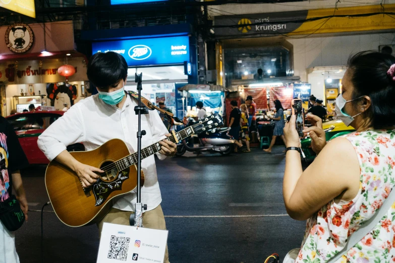 people playing guitars in the street at night