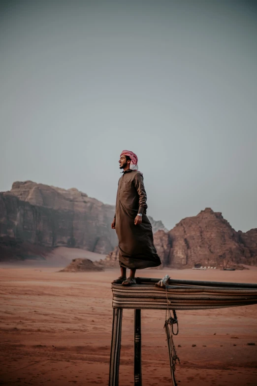 a woman is standing on a fence in a field