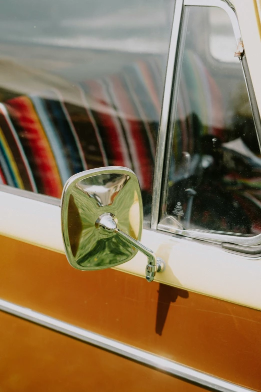 side view mirror of a yellow car that has different striped seat covers