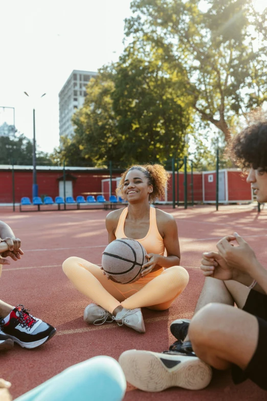 three young men and women sitting around playing basketball