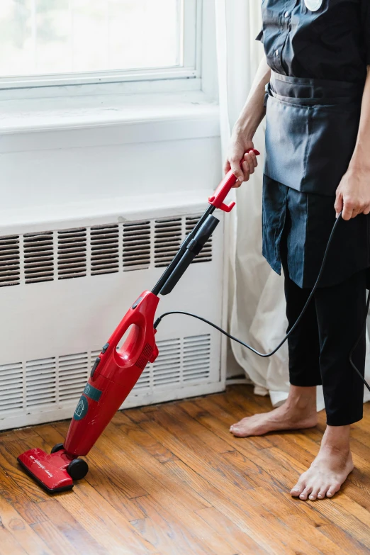 a woman in an apron is using a vacuum on the floor