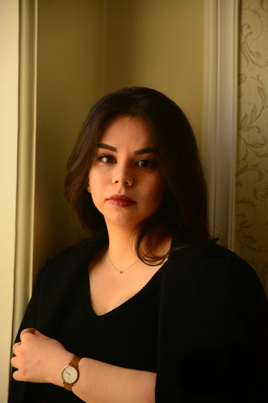 a woman looking into the camera while standing near a wall