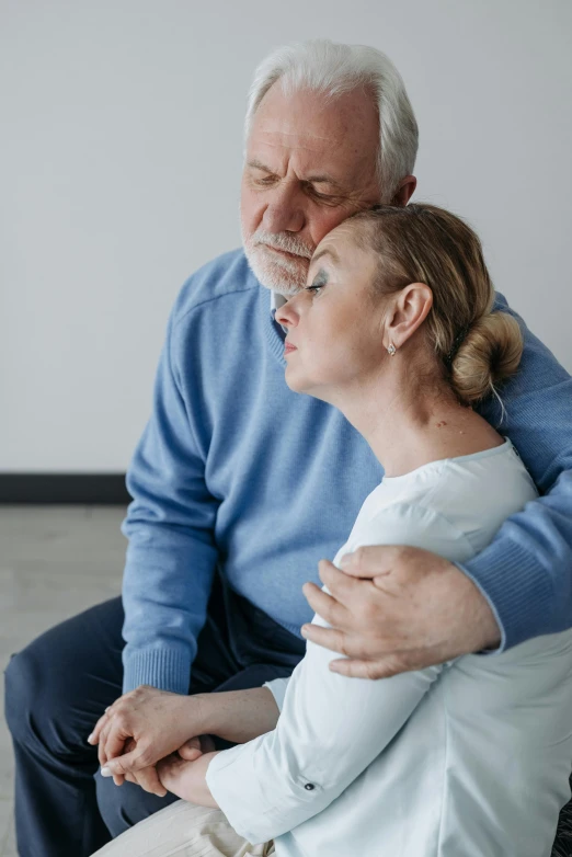 an older couple is sitting together with their arms around each other