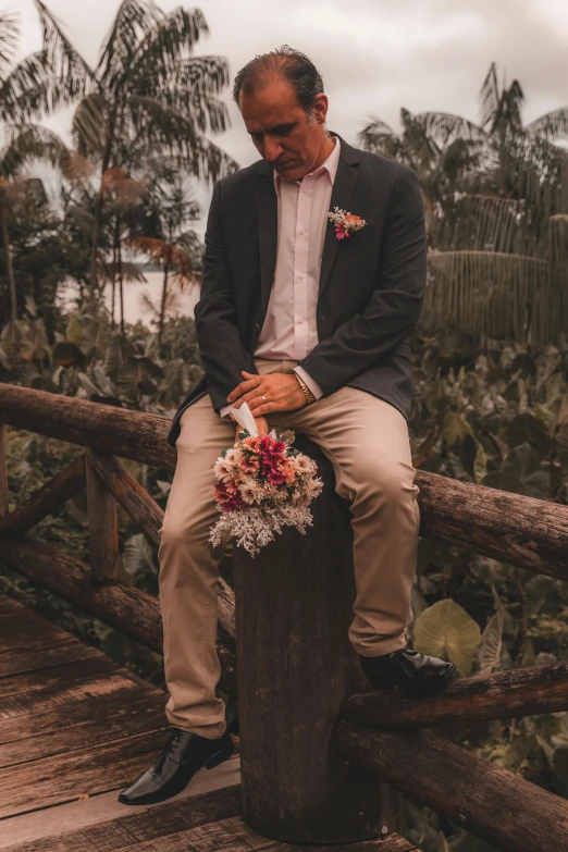 a man sits on a fence as he adjusts his shoes