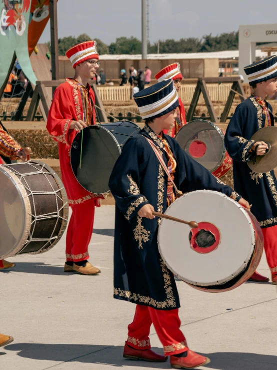 people in colorful dress playing drums on the street