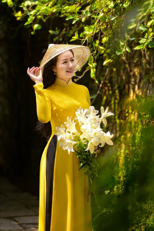 a girl wearing a yellow dress and big hat posing