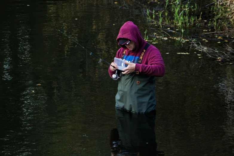 a person standing in water, holding a fish