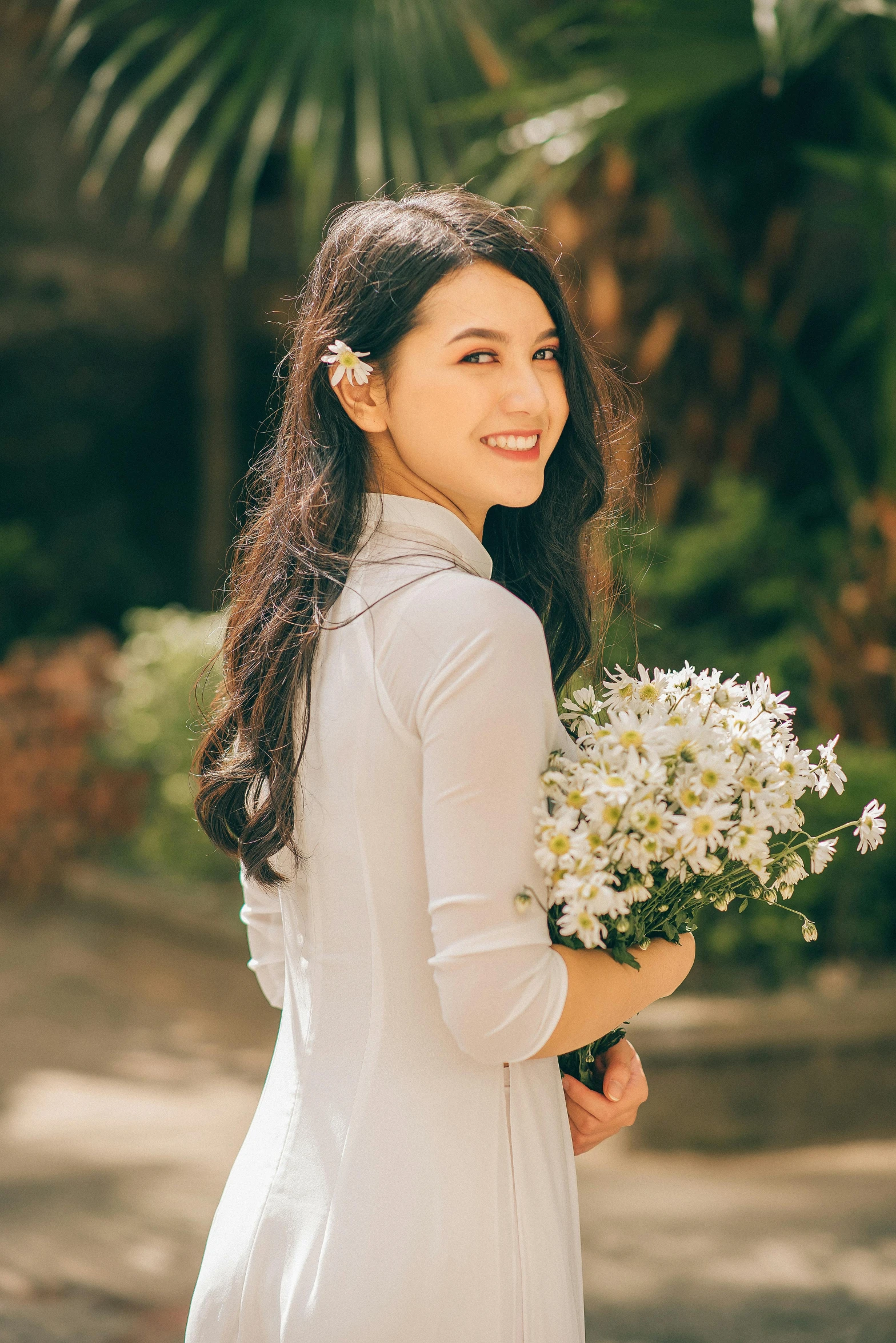 woman in white dress with bouquet of flowers standing outdoors