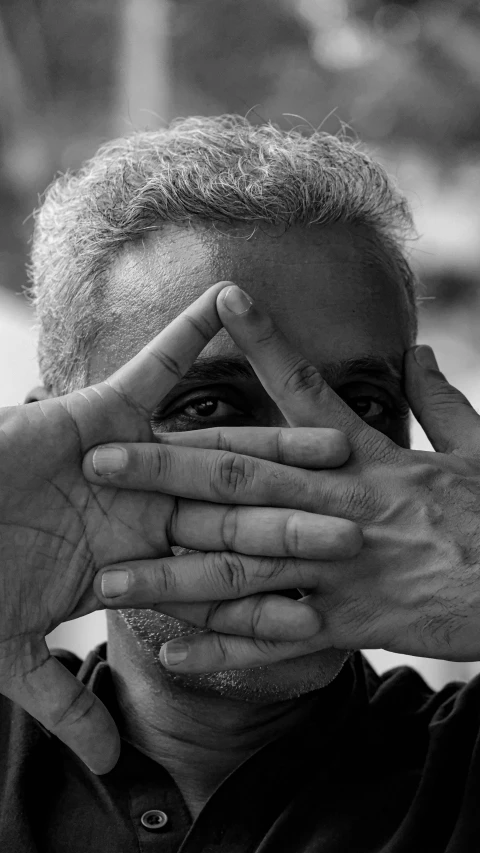 a black and white image of a man covering his eyes