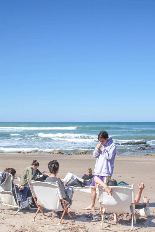 four people sitting on chairs on the beach