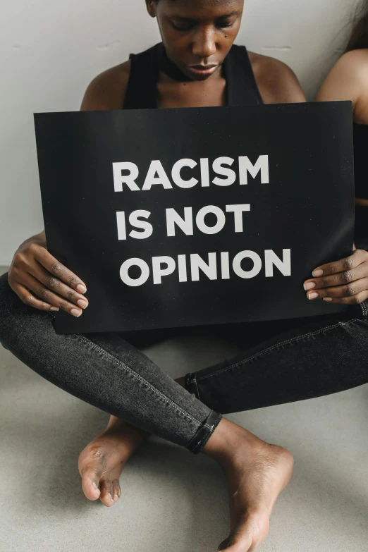 a black woman holding a black sign with racism is not opinion