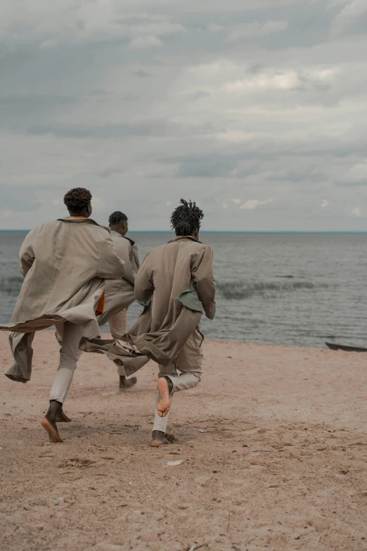 three men running on the beach near the ocean