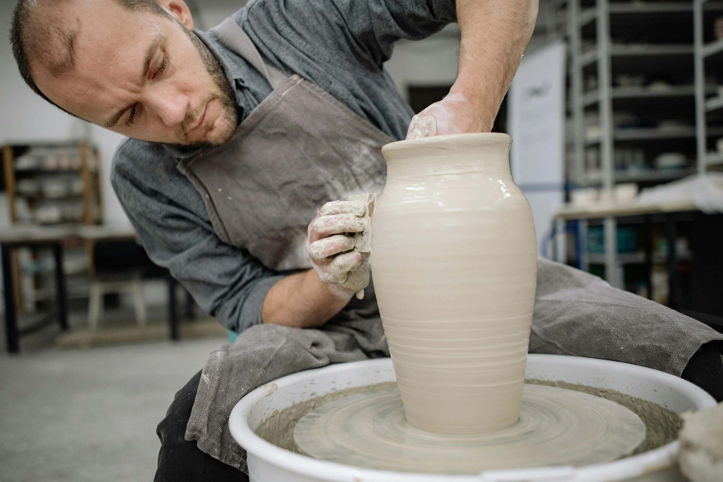 a man standing in a pottery factory working on a pot