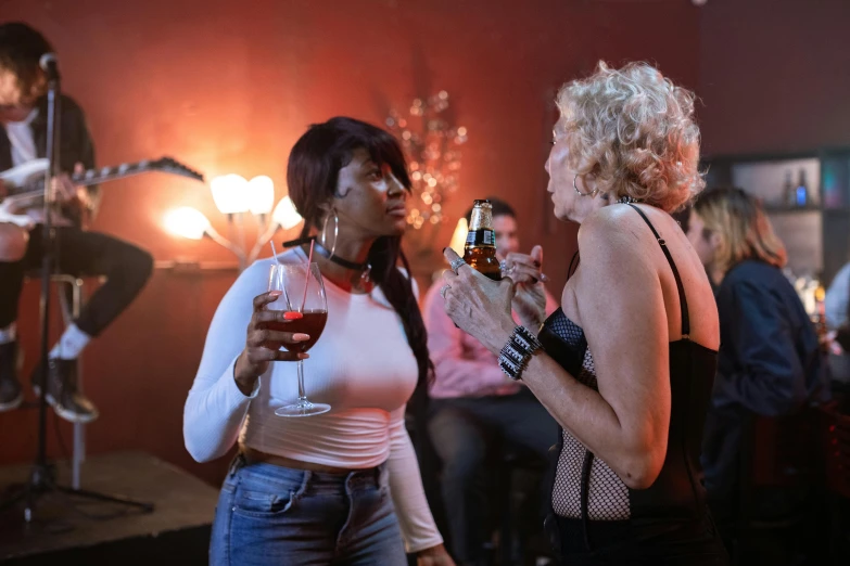 two women at a party, one holding a drink and one wearing fishnet stockings