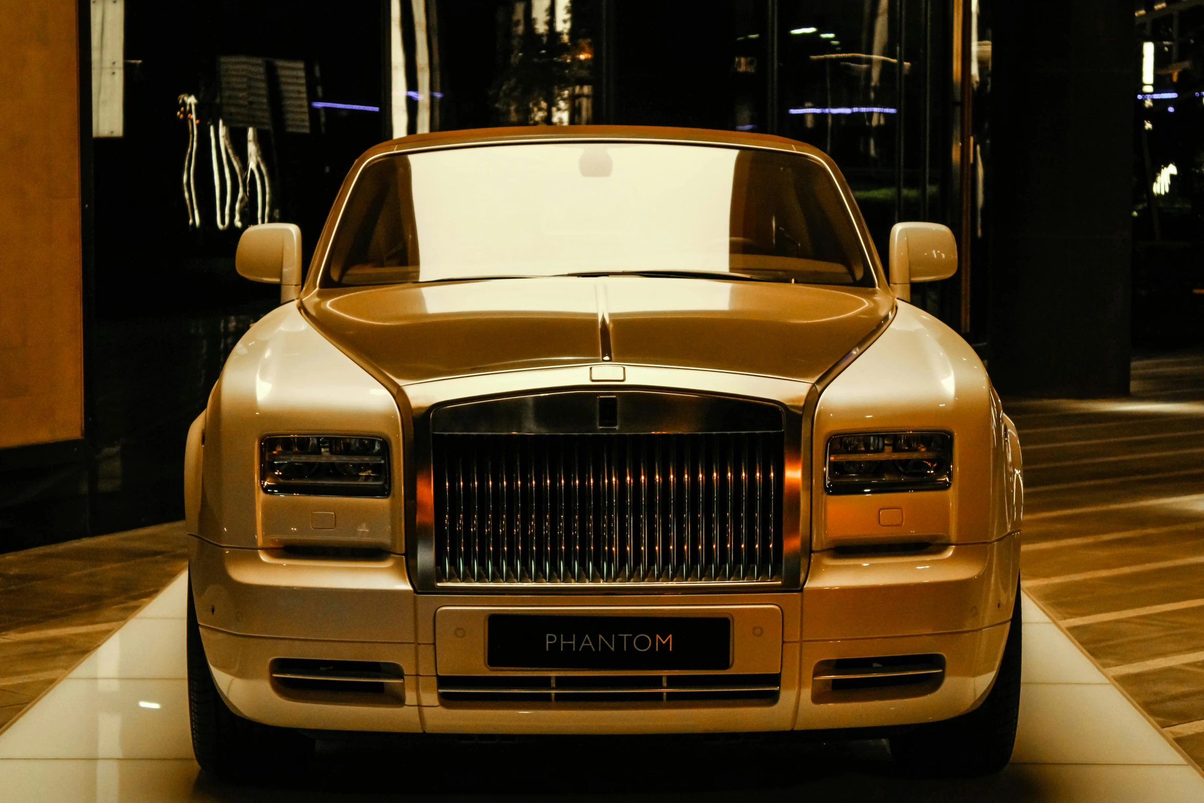 the front end of a shiny gold car parked on a tiled surface