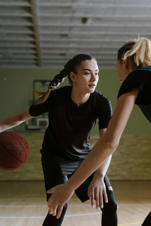 two women are playing basketball together in the gym