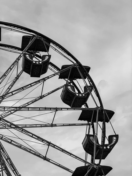 black and white pograph of ferris wheel against a cloudy sky