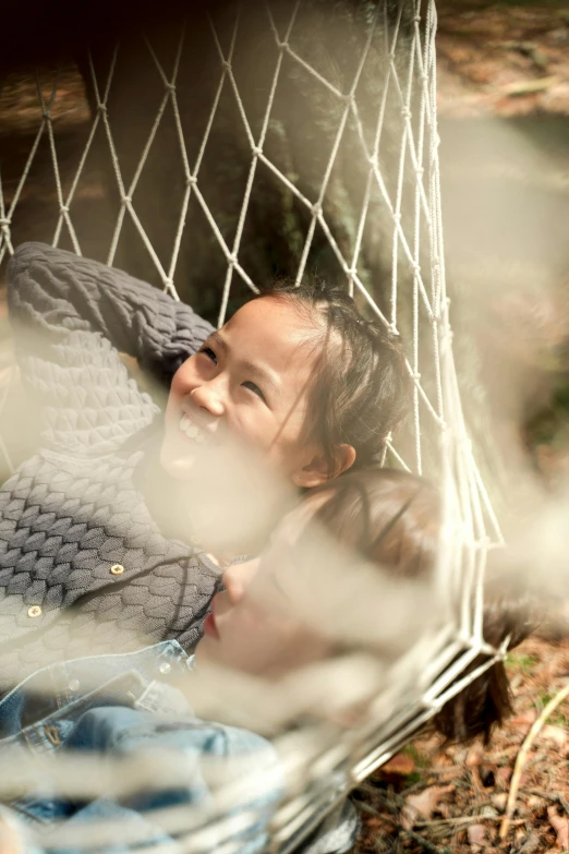 two children are looking out of a hammock