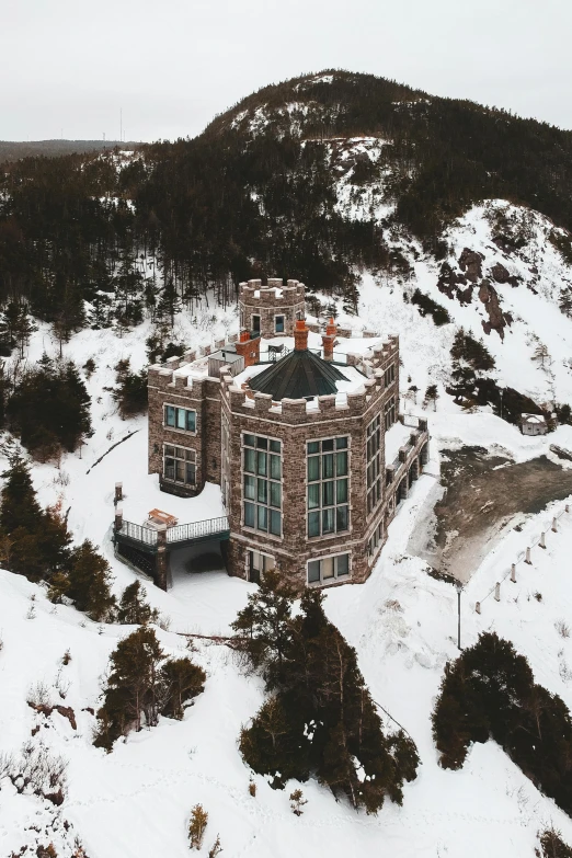 an aerial view of an old building surrounded by snowy mountains